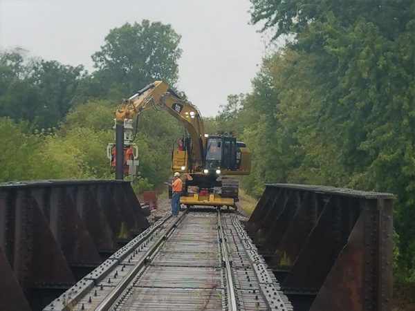 Sheet pile walls were installed to help reinforcing a railway bridge using a Grizzly MG-60 driver mounted on a brand-new CAT 329F.