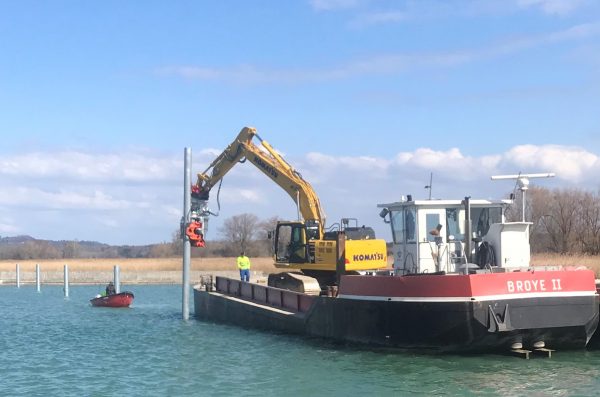 Un vibrofonceur à prise latérale MG-60 sur une pelle Komatsu PC-290 a été utilisé afin de planter des tubes de 12 pouces pour un projet d'amarrage de bateaux.